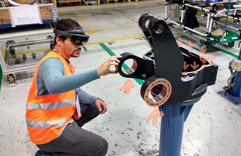 Human male worker is building a robot on Comau's shopfloor. He's looking at his task through augmented reality glasses